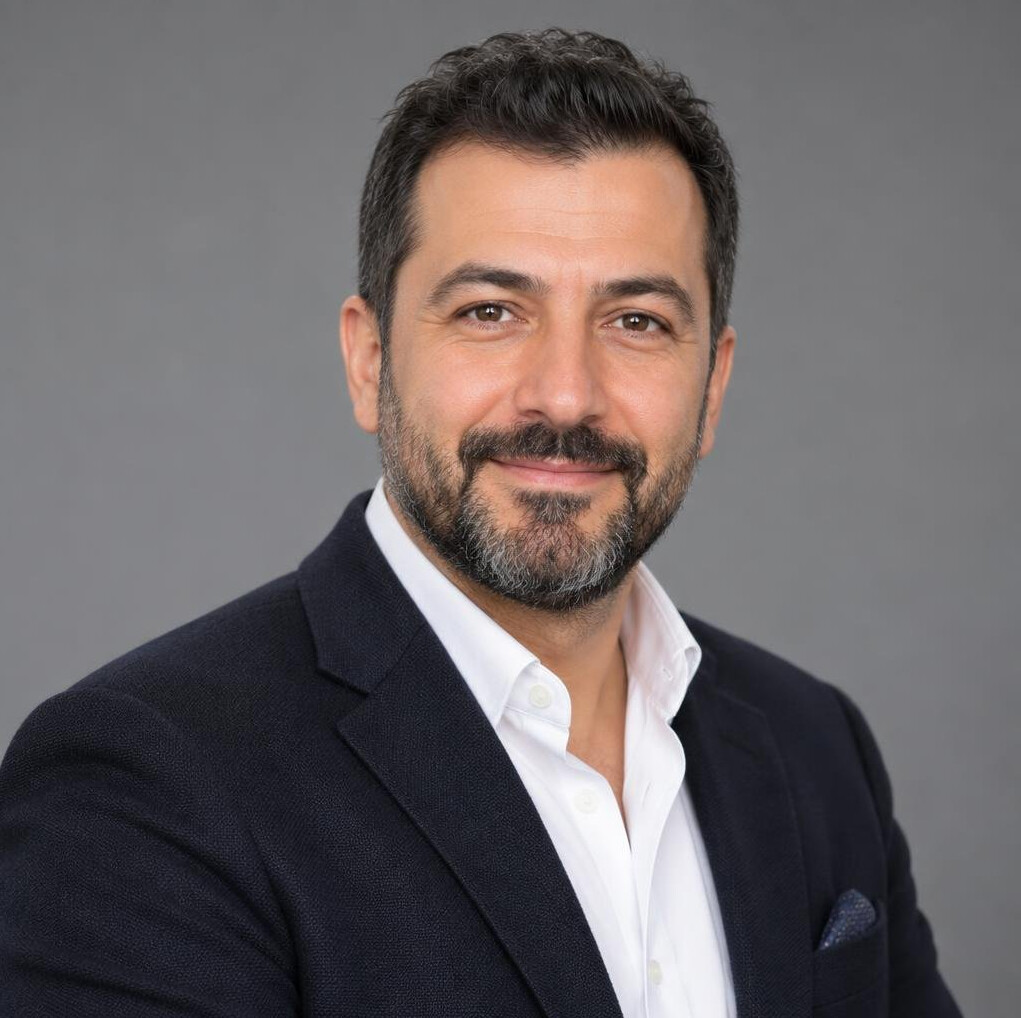 Turkish man in his 40s with short beard smiling in studio attire